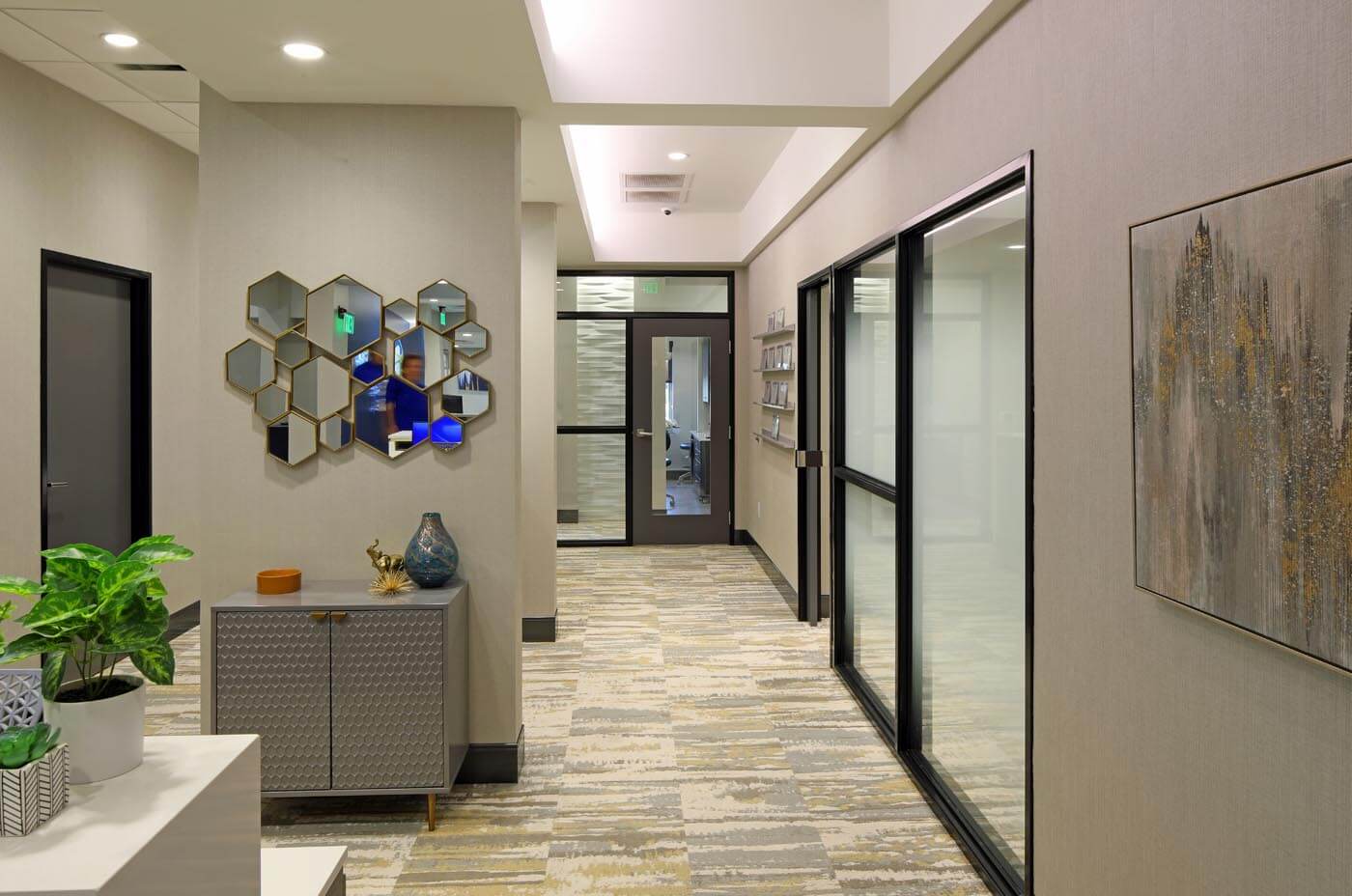 A view of the SkyRidge Dental lobby. Minimalist, soothing art hangs on the walls alongside potted plants and cozy furniture.