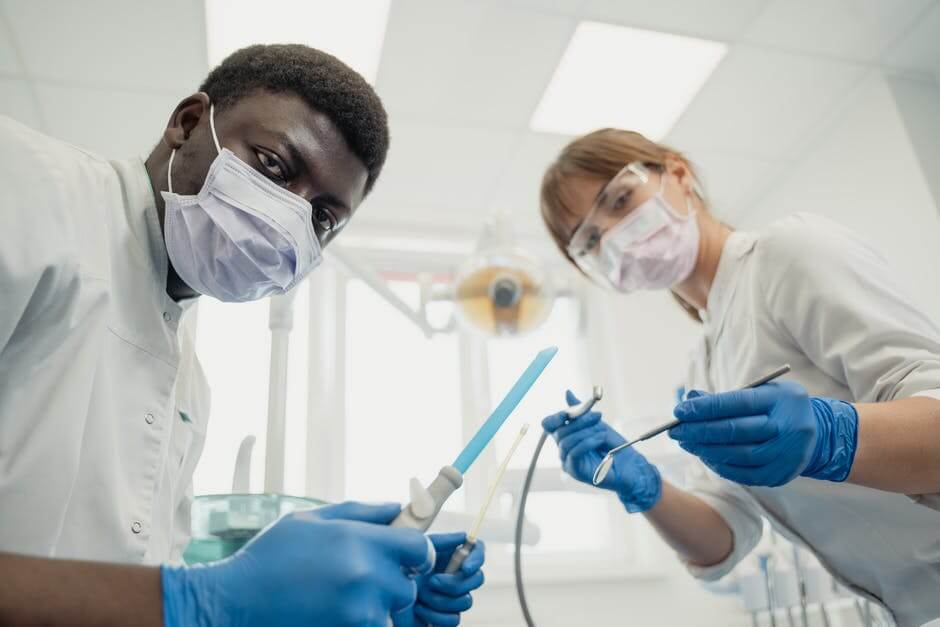 A photo of two dental professionals holding exam equipment.